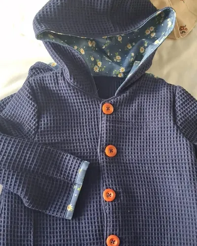 Chaqueta de bebé con capucha y botones naranjas, hecho por Tamara, costurera en Mairena del Aljarafe